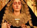 Imagen de una Virgen con vestimenta dorada y un halo, sosteniendo un objeto en sus manos.