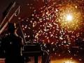 Un pianista toca el piano en un escenario iluminado por una luz brillante, mientras caen confeti alrededor.