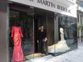 Tienda de moda con maniquíes vestidos y una mujer en la entrada.