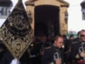 Un grupo de hombres en uniforme militar con banderas y instrumentos musicales, frente a una estructura histórica.