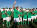 Equipo de fútbol celebrando una victoria, todos vestidos con camisetas verdes y calcetines verdes.