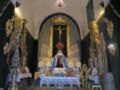 Interior de una iglesia con altar ornamental y estatuas de la Virgen María y Cristo crucificado.