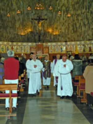 Misa en iglesia con sacerdotes y fieles. Altar, coro y vitrales.
