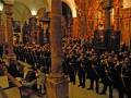 Concierto de banda militar en un interior de iglesia con columnas y altares ornamentados.