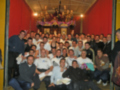 Grupo de personas en una fiesta navideña, con decoraciones y un altar en el fondo.