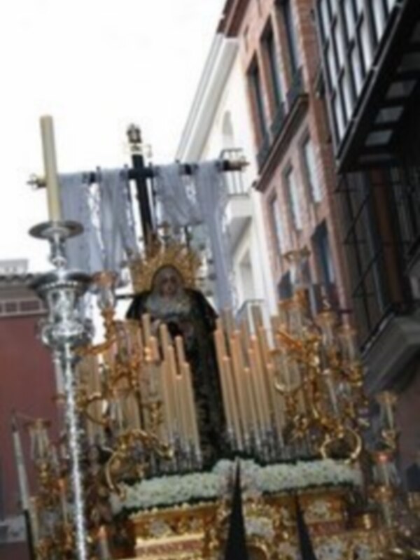 Imagen de una procesión religiosa en un templo, con una imagen venerada en medio de un altar elaborado y luces doradas.
