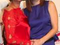 Dos mujeres posan juntas en un evento, una con vestido rojo y la otra con vestido azul. La imagen parece ser de un evento cultural o artístico, posiblemente relacionado con la cultura flamenca.