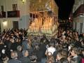 Procesión religiosa nocturna con una imagen de la Virgen María portada por devotos, rodeada por una multitud en una calle urbana.