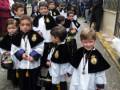 Niños vestidos con trajes tradicionales en una procesión religiosa.