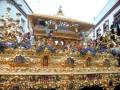 Un altar dorado con adornos florales y figuras religiosas en un entorno religioso.