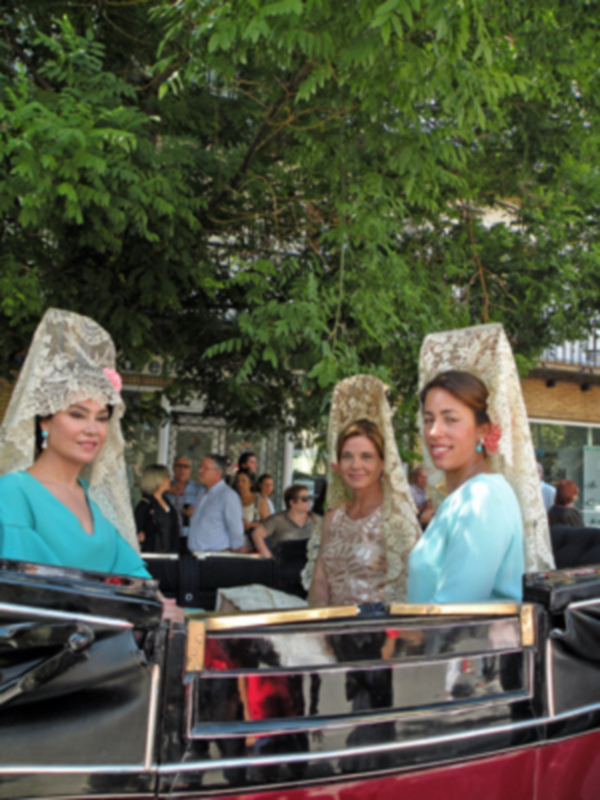 Tres mujeres vestidas con trajes tradicionales y mantas en un evento público, posiblemente durante una celebración cultural o religiosa.