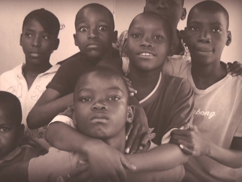 Una imagen en blanco y negro de varios niños africanos juntos, expresando diferentes emociones.