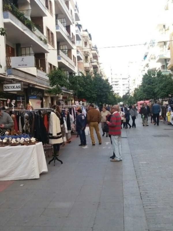Un mercado callejero en un barrio residencial con tiendas de ropa y artículos para el hogar.
