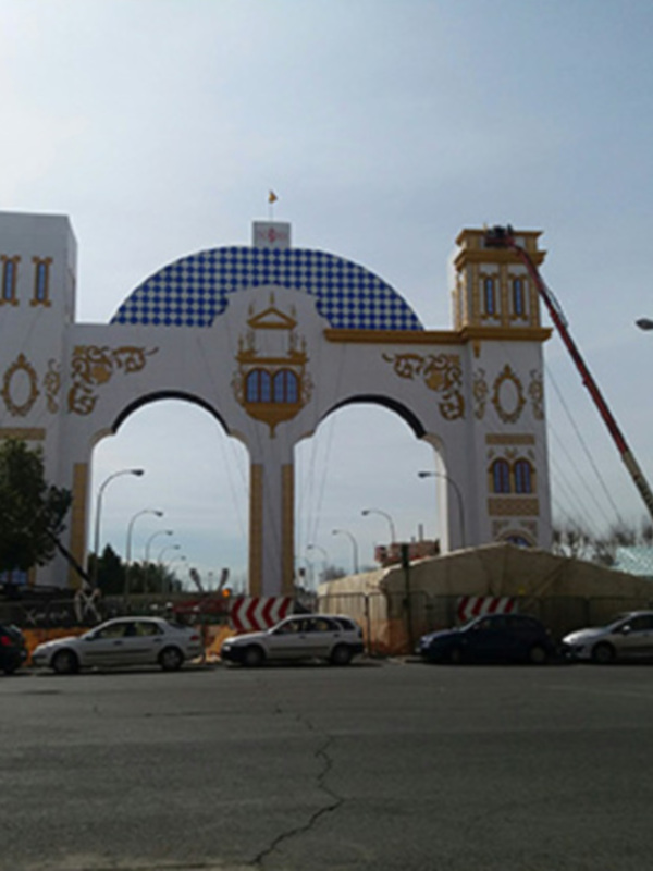 Puerta monumental con arcos y torres, en un entorno urbano con vehículos y estructuras de hormigón.