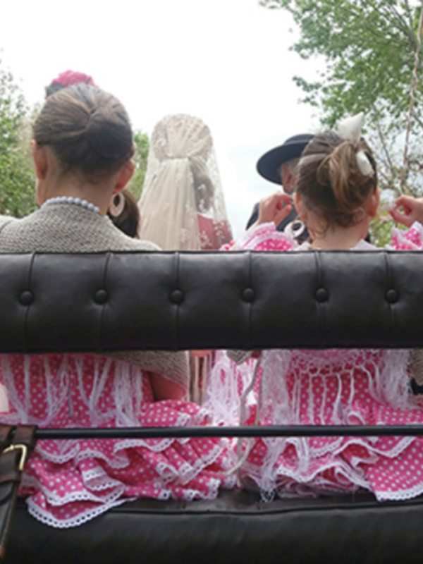 Fiestas tradicionales con vestimenta regional en un carro de caballos, celebración en España.