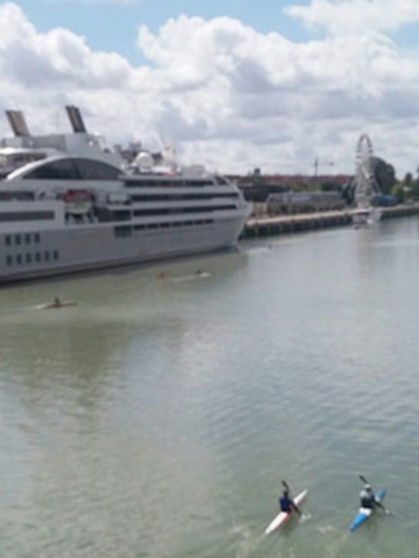 Paseo en kayak en el río Guadalquivir con un crucero en el fondo y una torre de la ciudad a la izquierda.