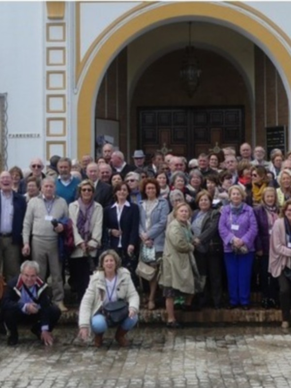 Grupo de personas posando frente a una iglesia con arcos y una imagen de la Virgen en el pórtico.