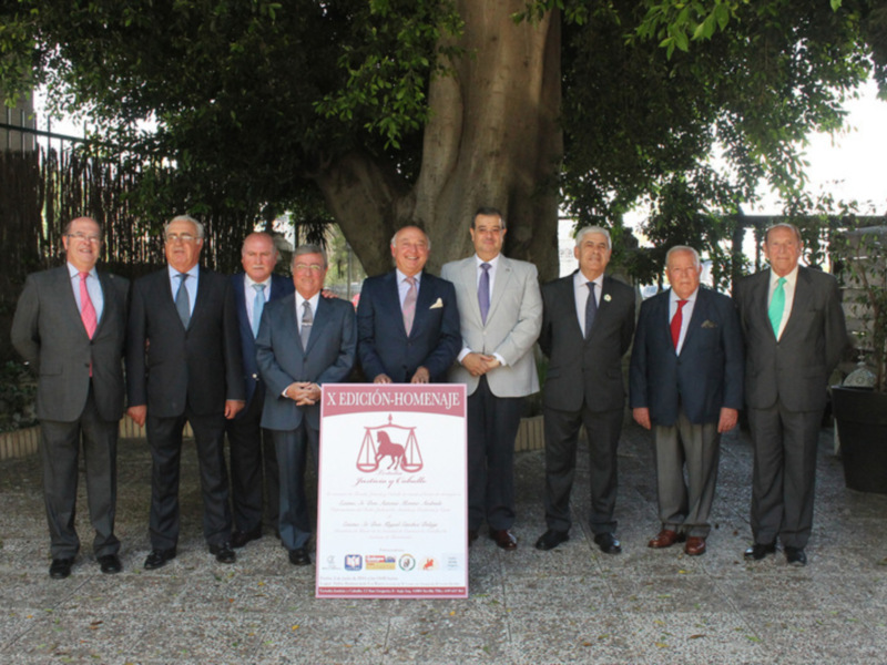 Celebración de la X Edición-Homenaje en un entorno al aire libre con un grupo de hombres en trajes formales.
