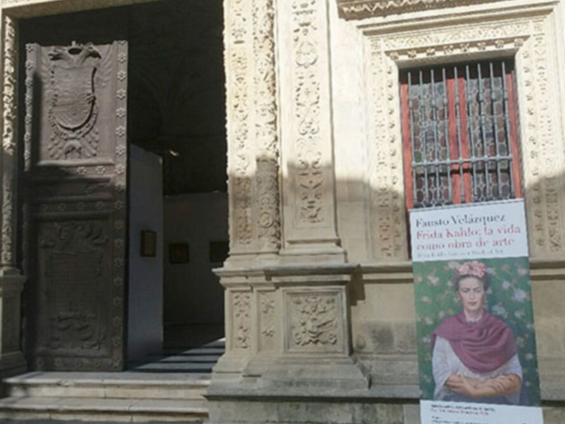 Entrada del Museo Casa de Frida Kahlo con cartel informativo sobre su vida como obra de arte.