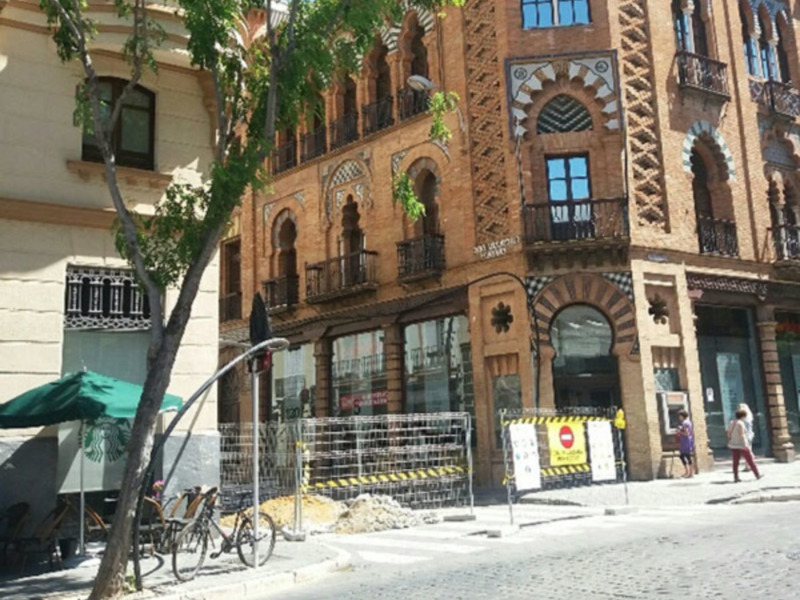 Arquitectura tradicional con detalles de azulejos y balcones en una calle de Sevilla.