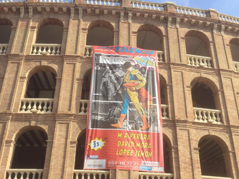 Torero en la plaza de toros de Valencia, España. Banner promocionando una corrida de toros el 23 de noviembre. Teléfono: 902 10 77 77. Información: www.losmadriz.com.
