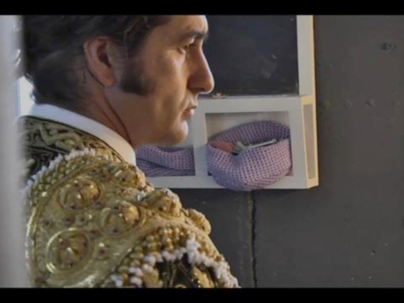 Matador in traditional attire looking intently at a small basket of flowers.