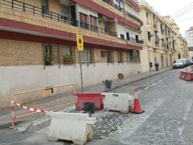 Tráfico detenido en calle con barreras de construcción y señal de peligro