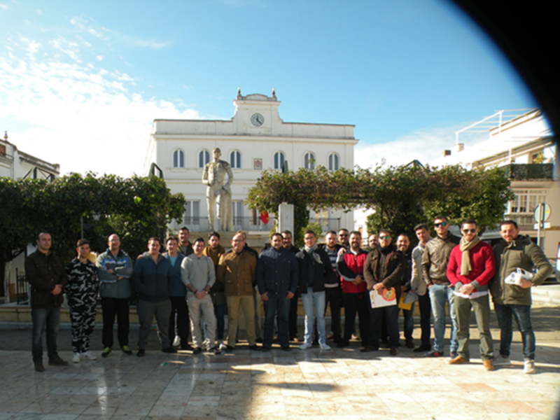 Grupo de personas posando frente a una estatua y un edificio histórico.