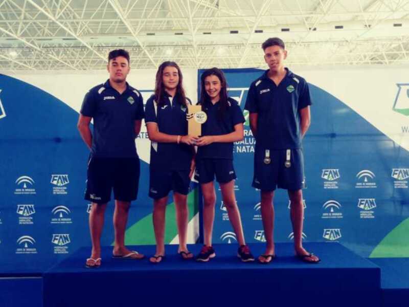 Los cuatro nadadores posan con orgullo en el podio, celebrando su victoria en la Federación Andaluza de Natación.