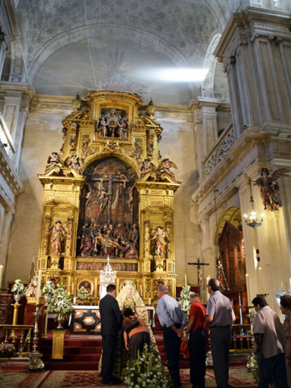 Altar de una iglesia con estatuas y flores en el centro.