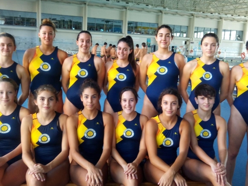 Equipo femenino de natación en un gimnasio, vestidos con trajes azules y amarillos.
