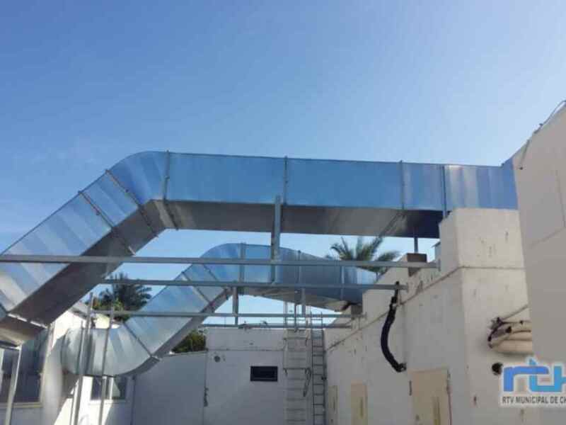 Instalación de conductos de ventilación en un edificio. El sistema incluye tuberías metálicas y paneles de cristal, diseñado para mejorar la circulación del aire. La imagen muestra una estructura moderna y funcional, típica de instalaciones industriales o comerciales.