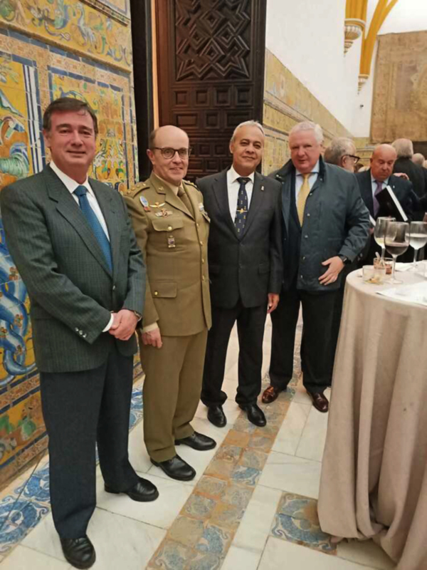 Grupo de personas en trajes formales y militar posando en un ambiente decorado con azulejos de cerámica.